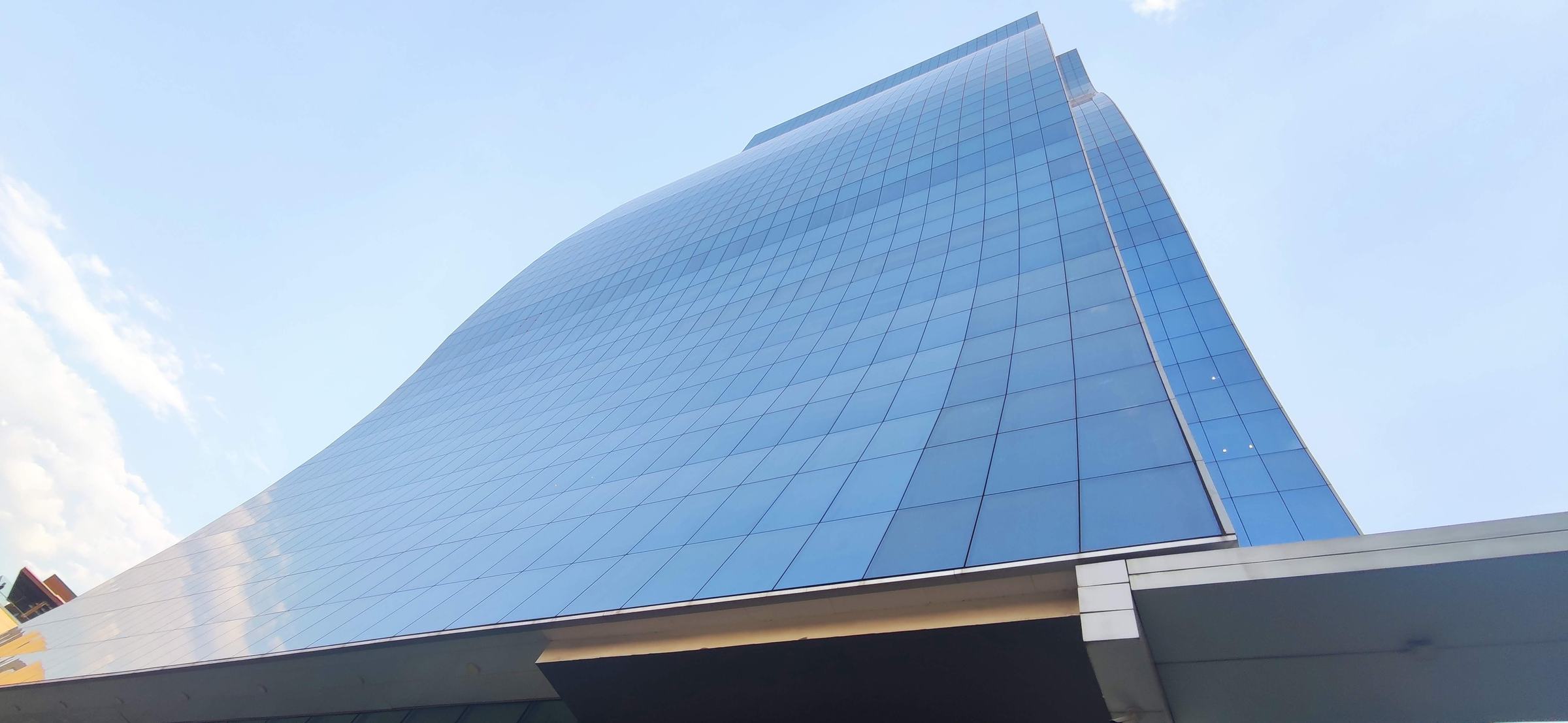 Torre corporativa de fachada acristalada curva vista en contrapicado