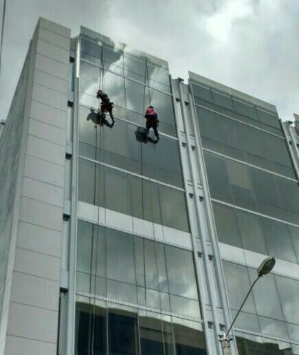 Dos operarios trabajando sobre la fachada acristalada de un edificio corporativo
