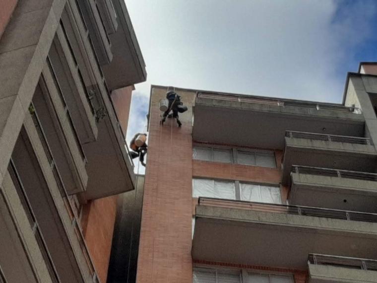 Dos operarios descolgados interviniendo la fachada de un edificio residencial